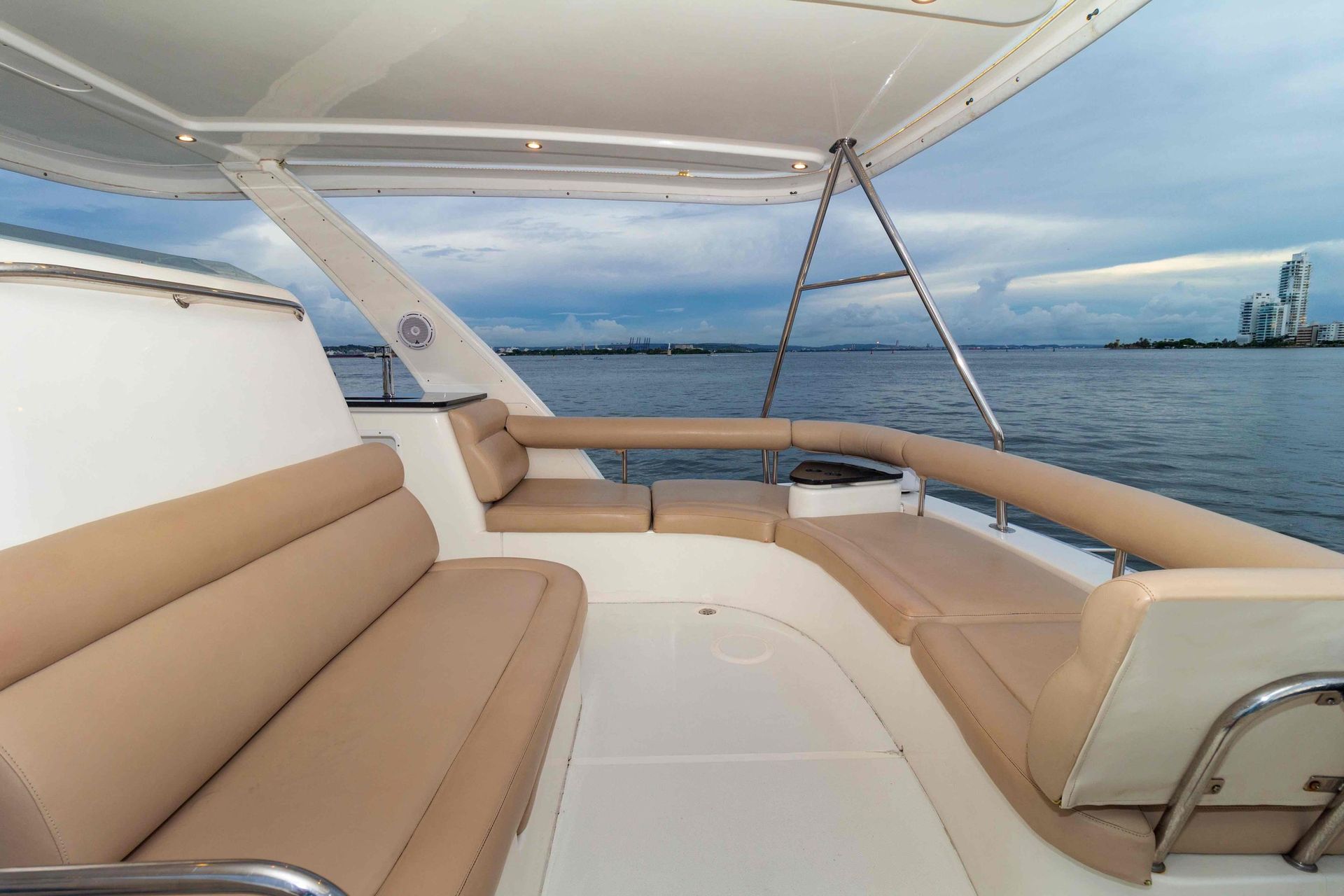 A boat with a couch on the deck is floating on top of a body of water.