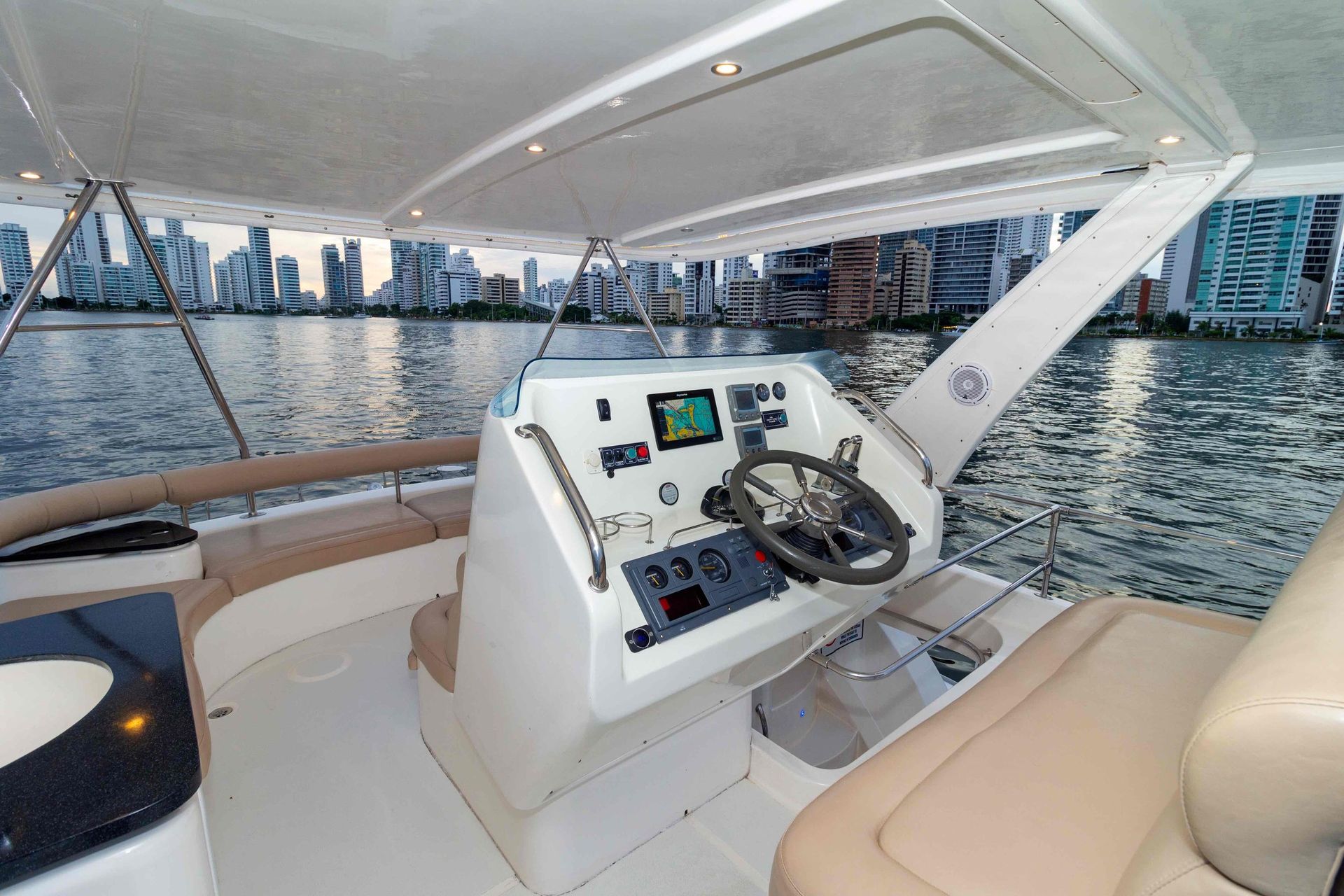 The cockpit of a boat with a steering wheel in the water.