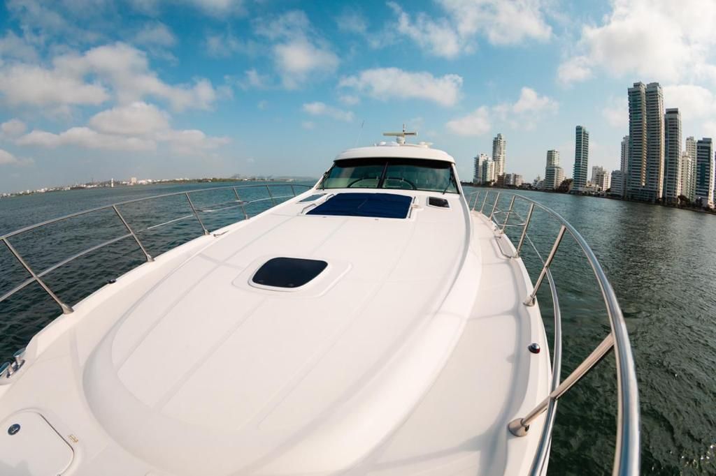 A white boat is floating on top of a body of water with a city in the background.
