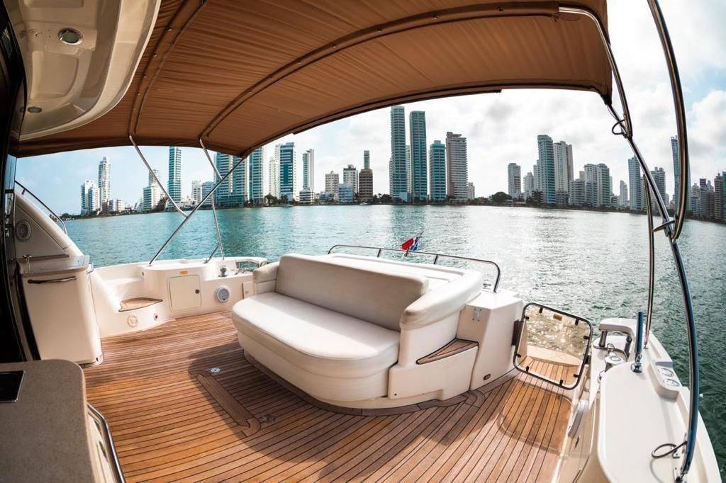 The back of a boat with a couch and a canopy overlooking a city.