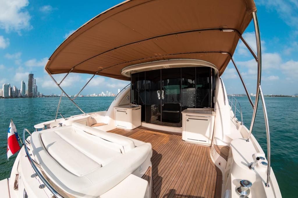 The back of a yacht with a canopy and a wooden deck.