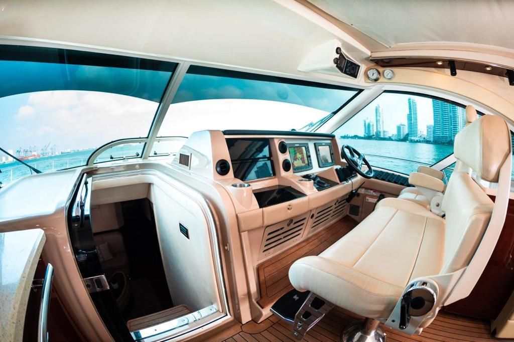 The interior of a boat with a white seat and steering wheel.