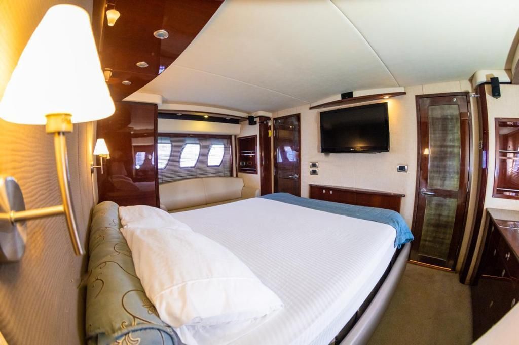 A bedroom on a boat with a large bed and a flat screen tv.