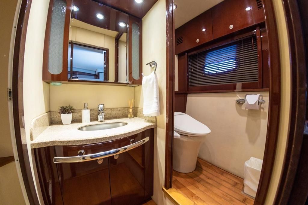 A bathroom on a boat with a sink , toilet and mirror.