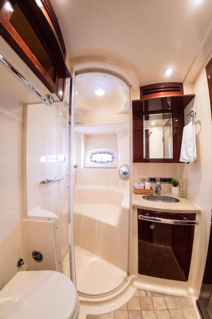 A bathroom on a boat with a toilet , sink and shower.