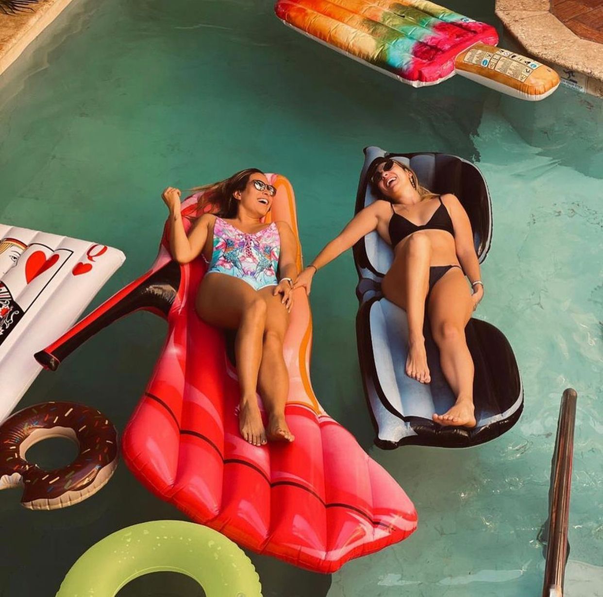 Two women are laying on rafts in a pool