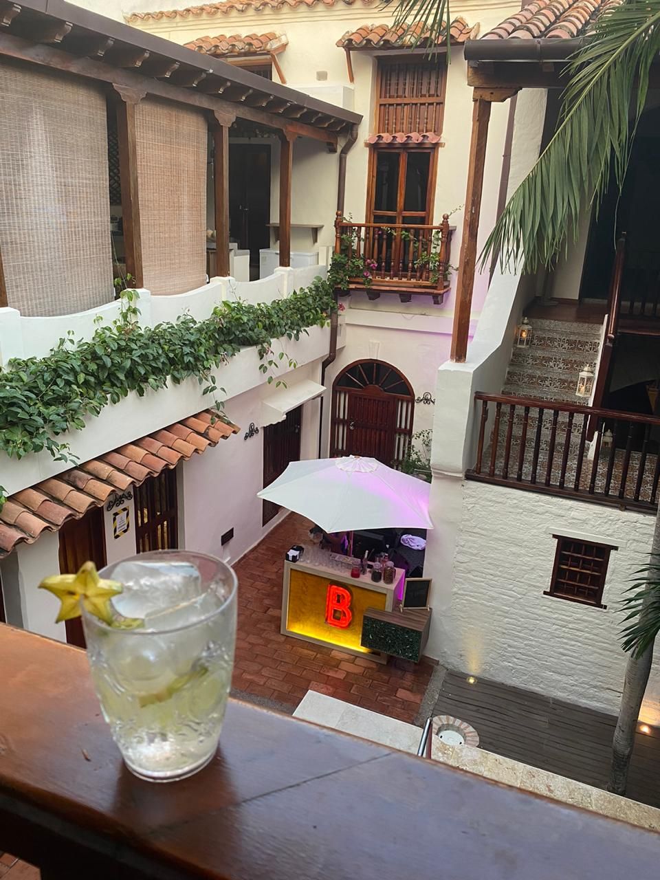 A drink with a star on it is on a balcony overlooking a courtyard.