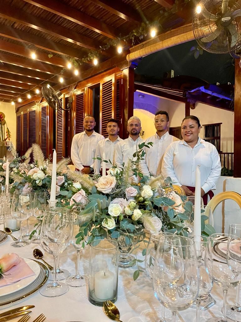 A group of men are standing around a table with flowers and candles.