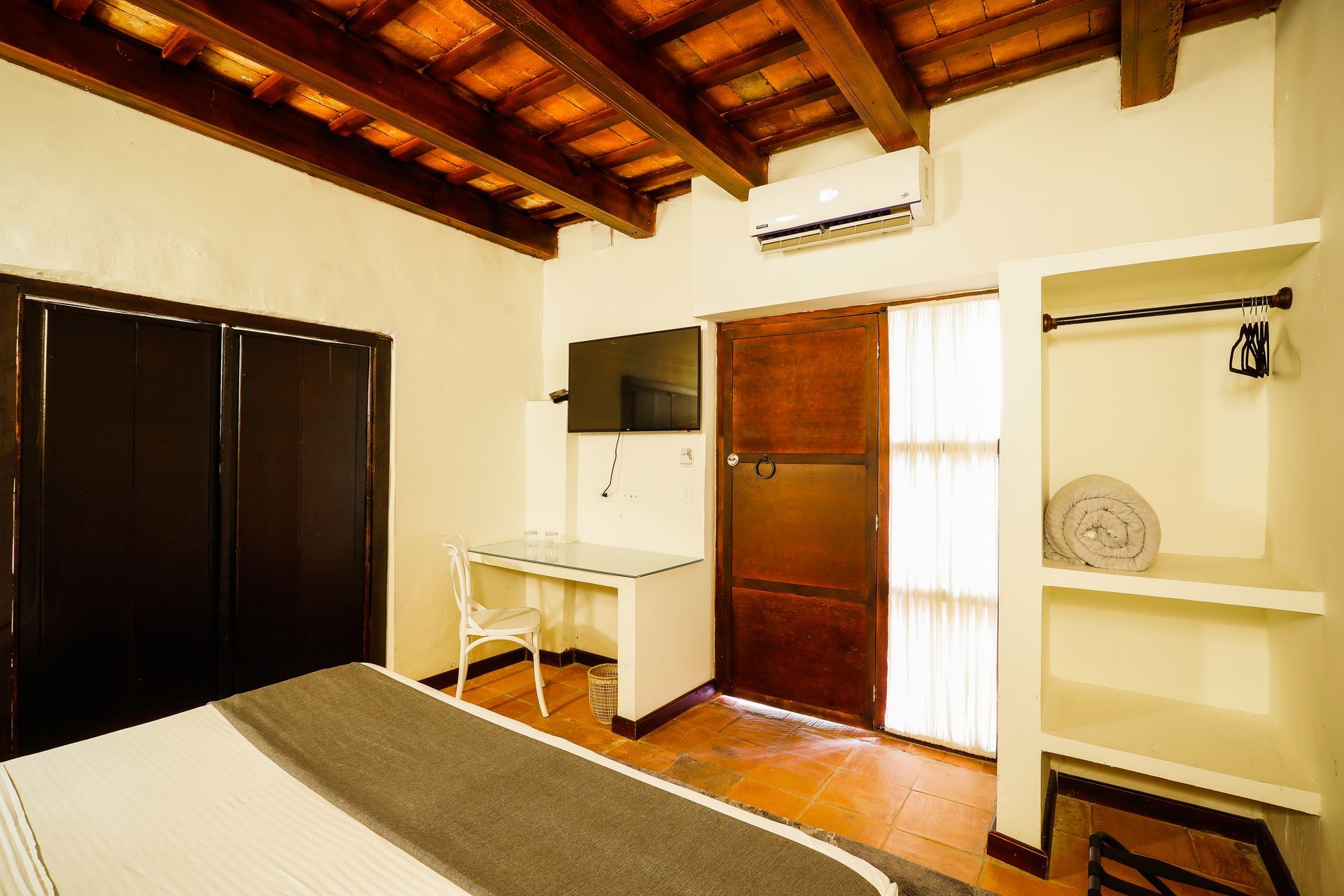 A hotel room with a bed , desk , chair and television.