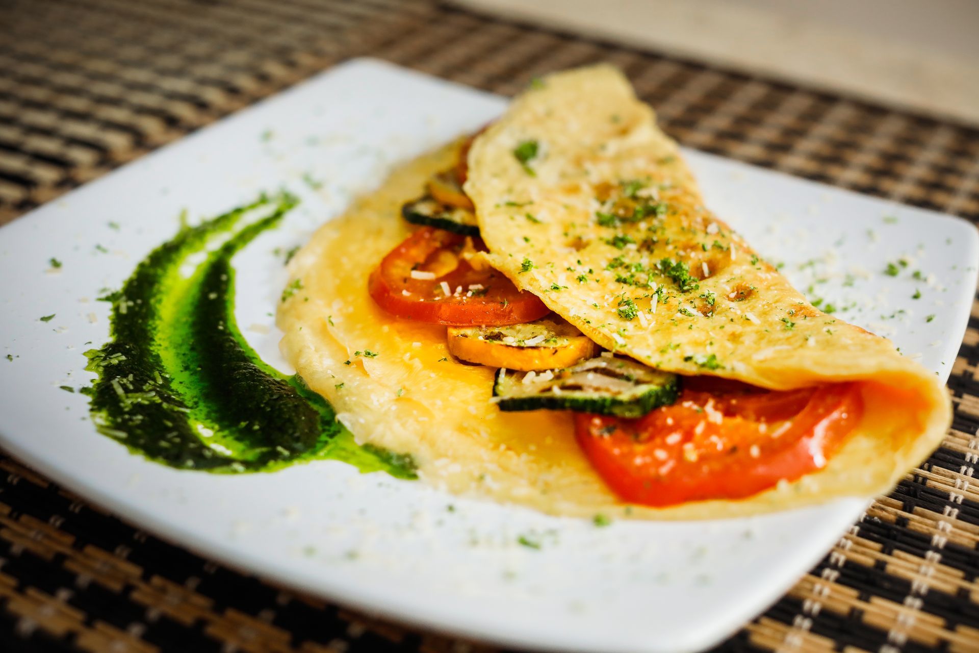 A white plate topped with a tortilla with tomatoes and zucchini on it.