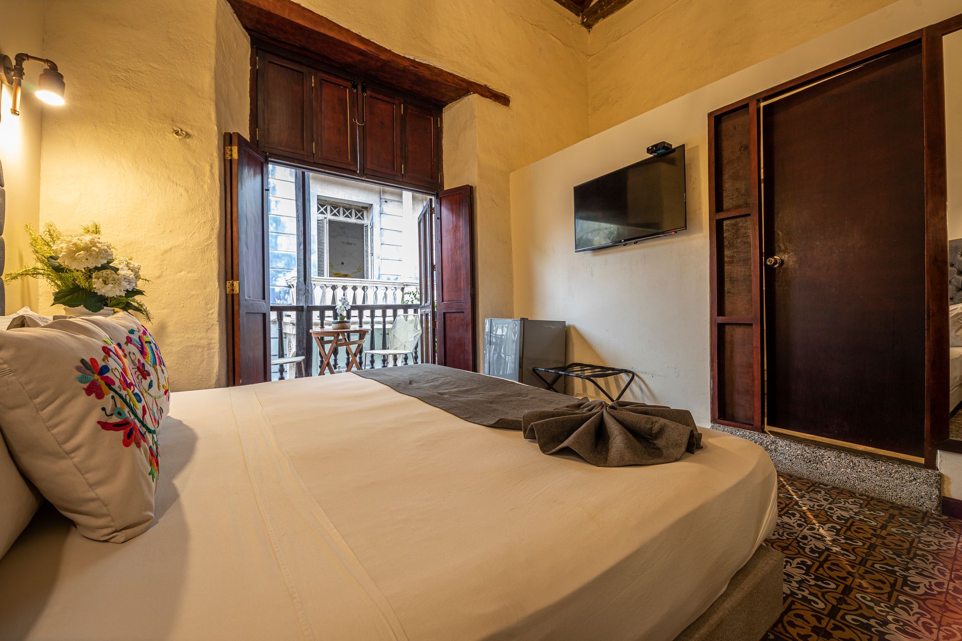 A hotel room with a bed , television , and balcony.