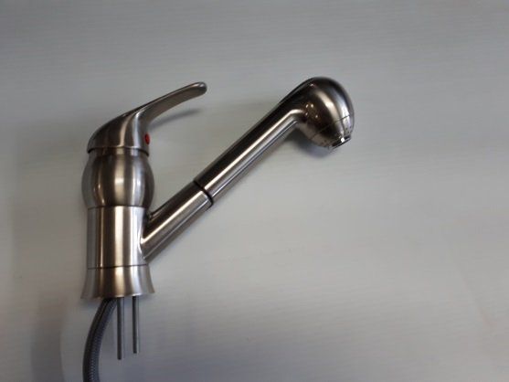Robinet de cuisine en métal brossé avec douchette extractible, posé contre un mur blanc uni.