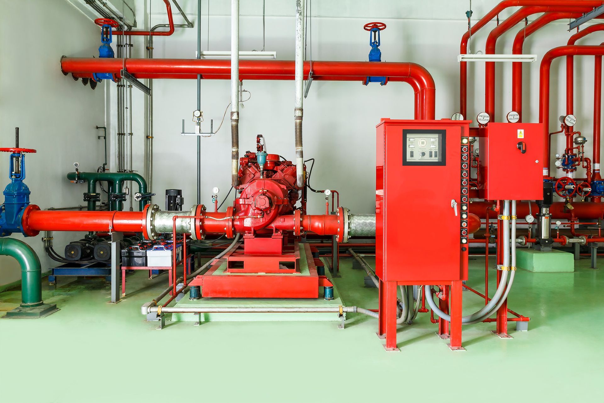 Fire pump room with red pipes, pump, and control panel. Fire pump room with red pipes, pump, and control panel.
