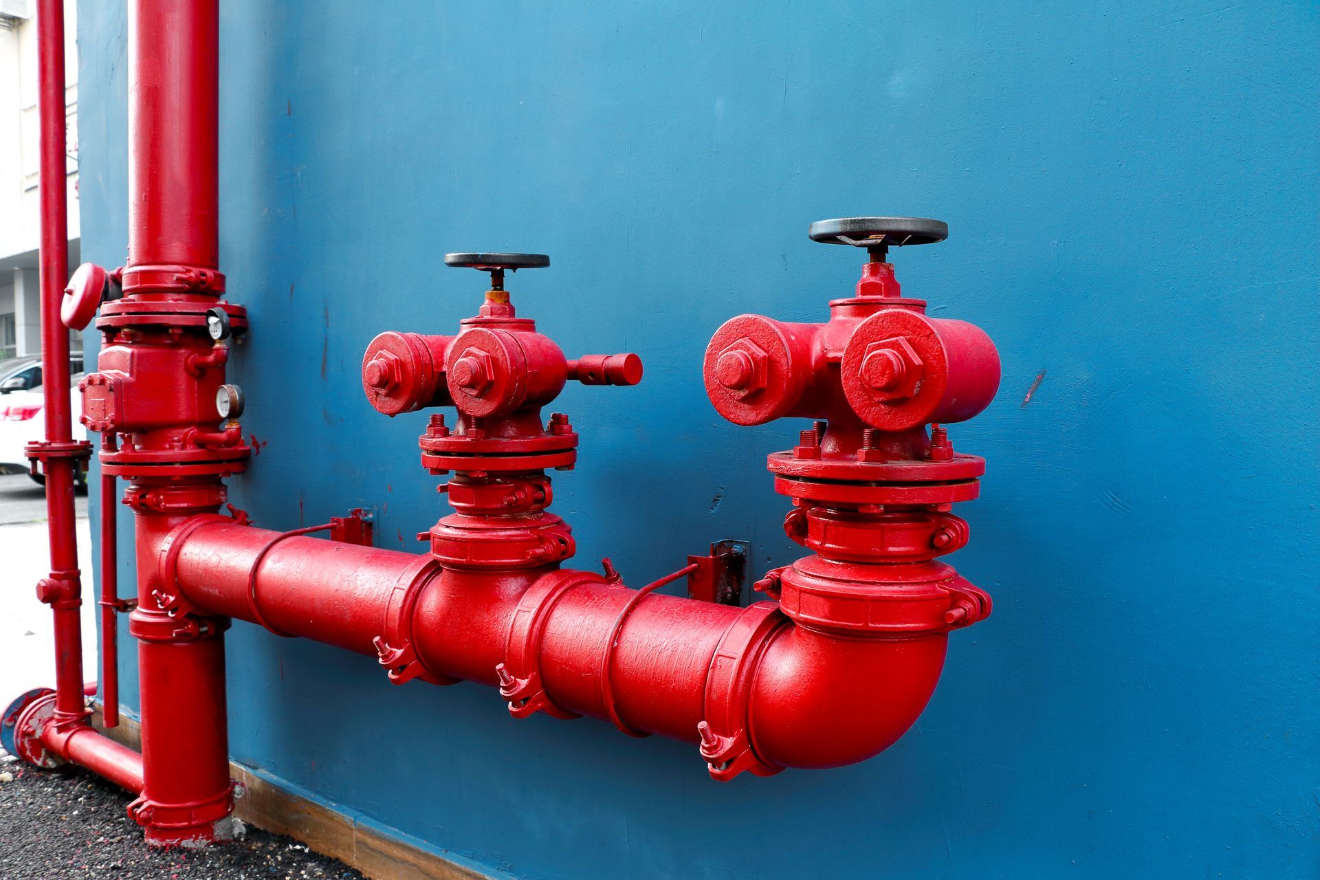 Red fire hydrant pipes against a blue wall. Red fire hydrant pipes against a blue wall.
