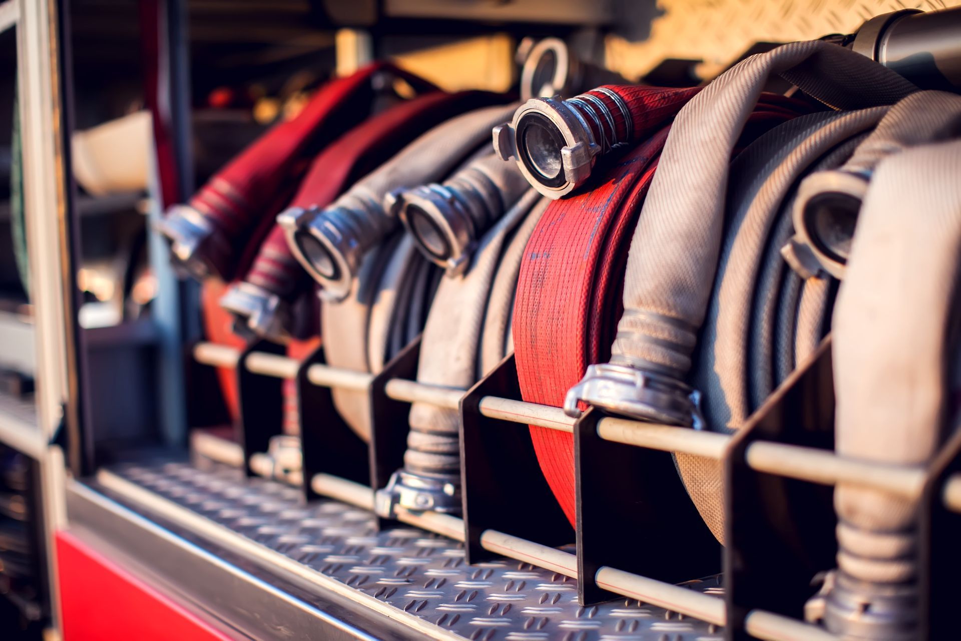 Coiled fire hoses in red, gray, and silver, stored on a fire truck. Coiled fire hoses in red, gray, and silver, stored on a fire truck.