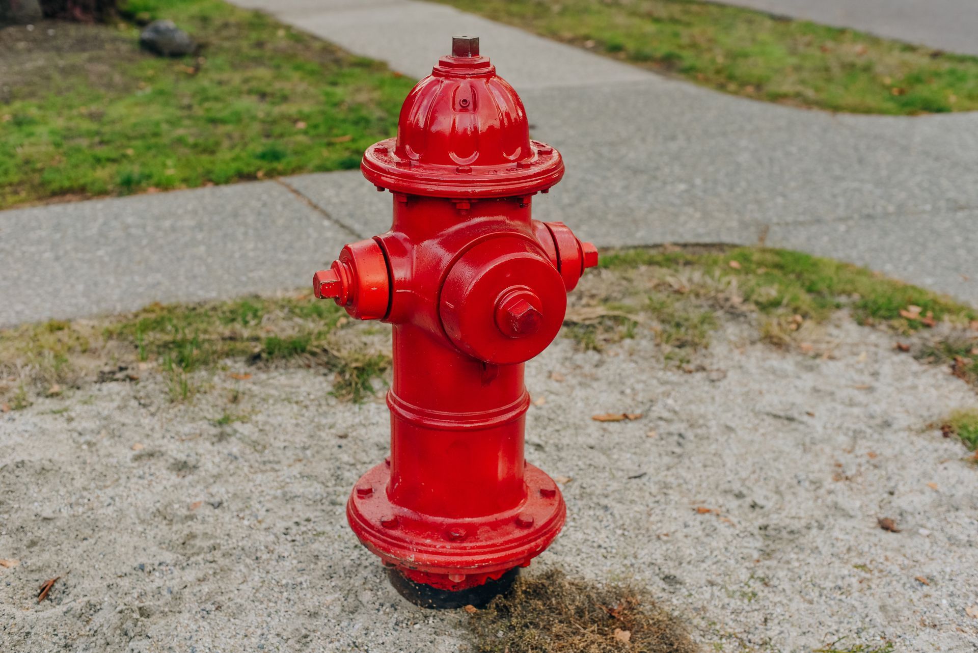 Red fire hydrant on a gravel patch beside a sidewalk and grass. Red fire hydrant on a gravel patch beside a sidewalk and grass.