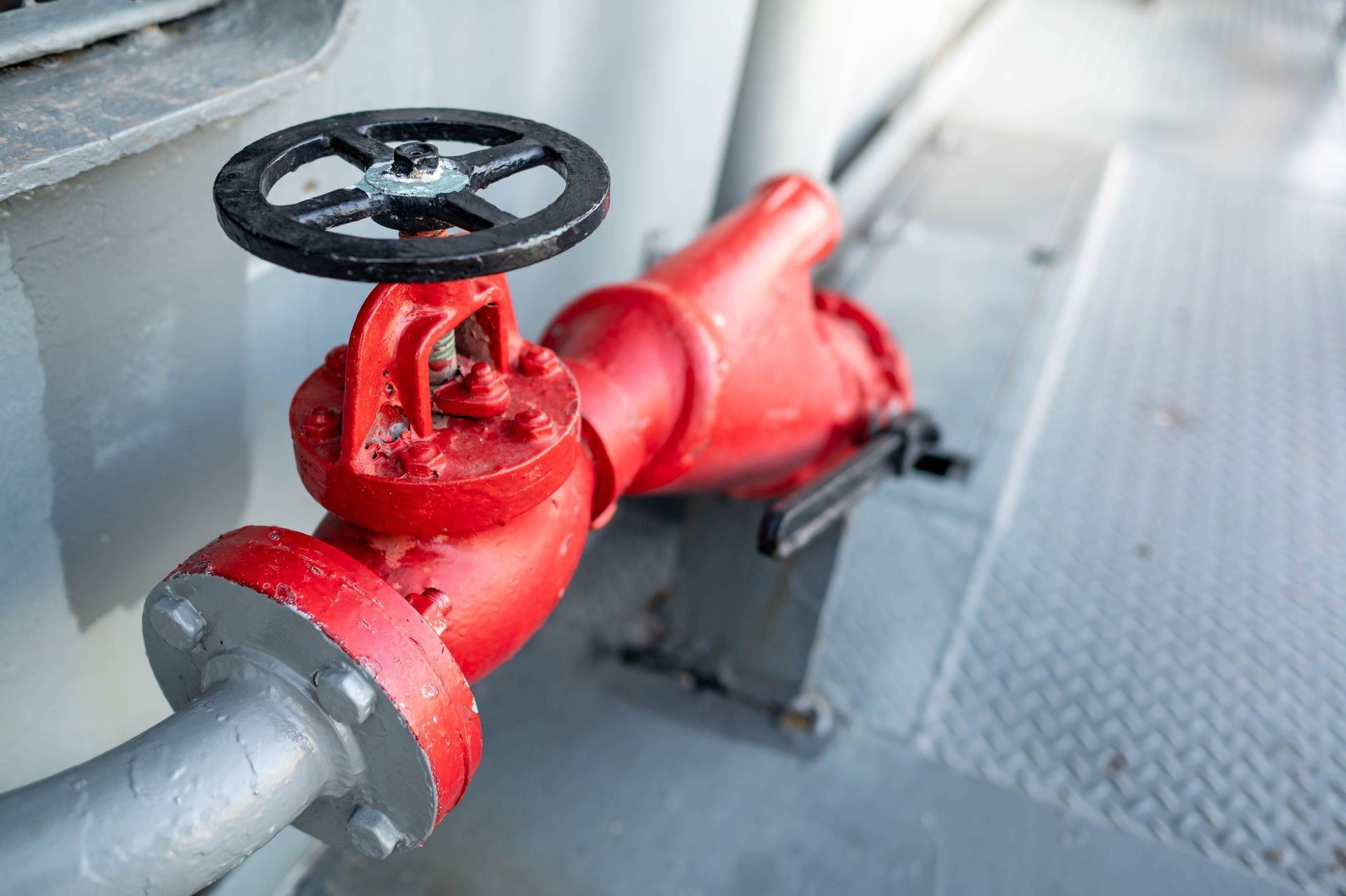 Red fire hydrant valve with a black handle on a silver pipe. Red fire hydrant valve with a black handle on a silver pipe.