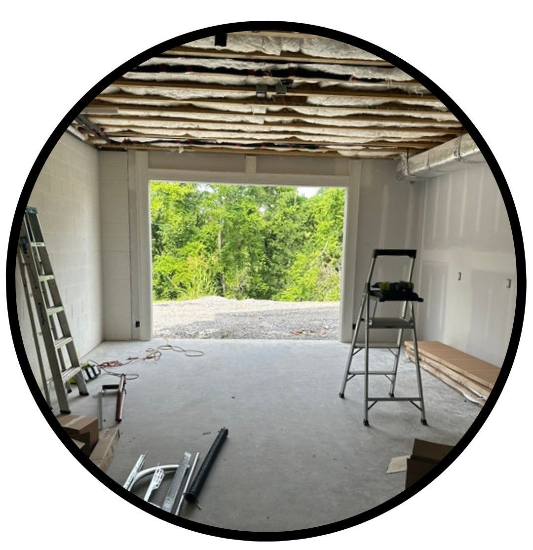 There is a ladder in the middle of a room with a garage door open.