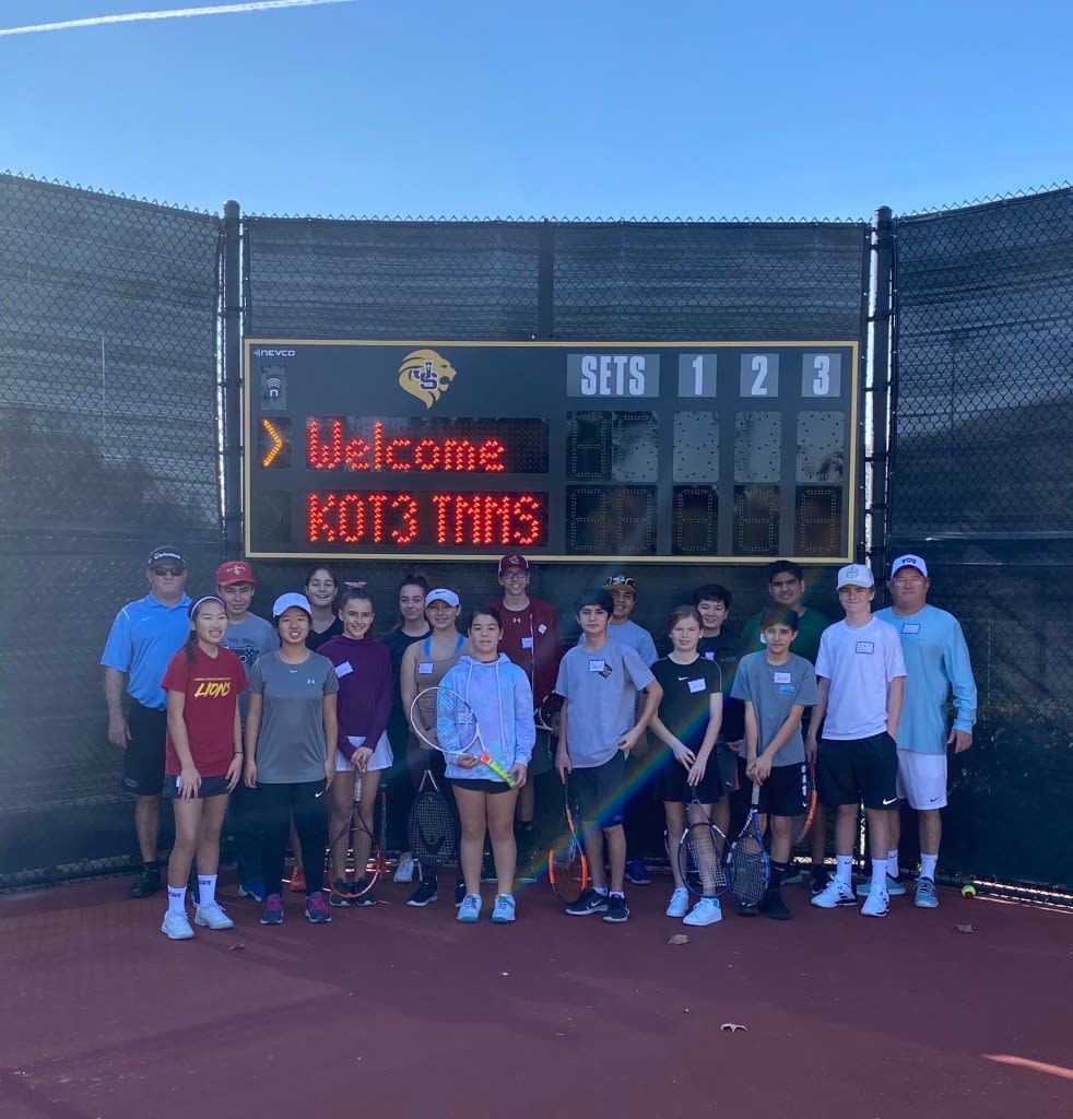 A group of people standing in front of a scoreboard that says welcome