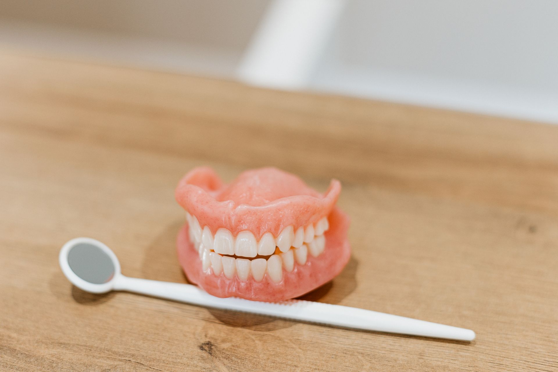 A Denture Is Sitting On A Wooden Table — Harvey Smiles Denture Clinic In Burleigh Heads, QLD
