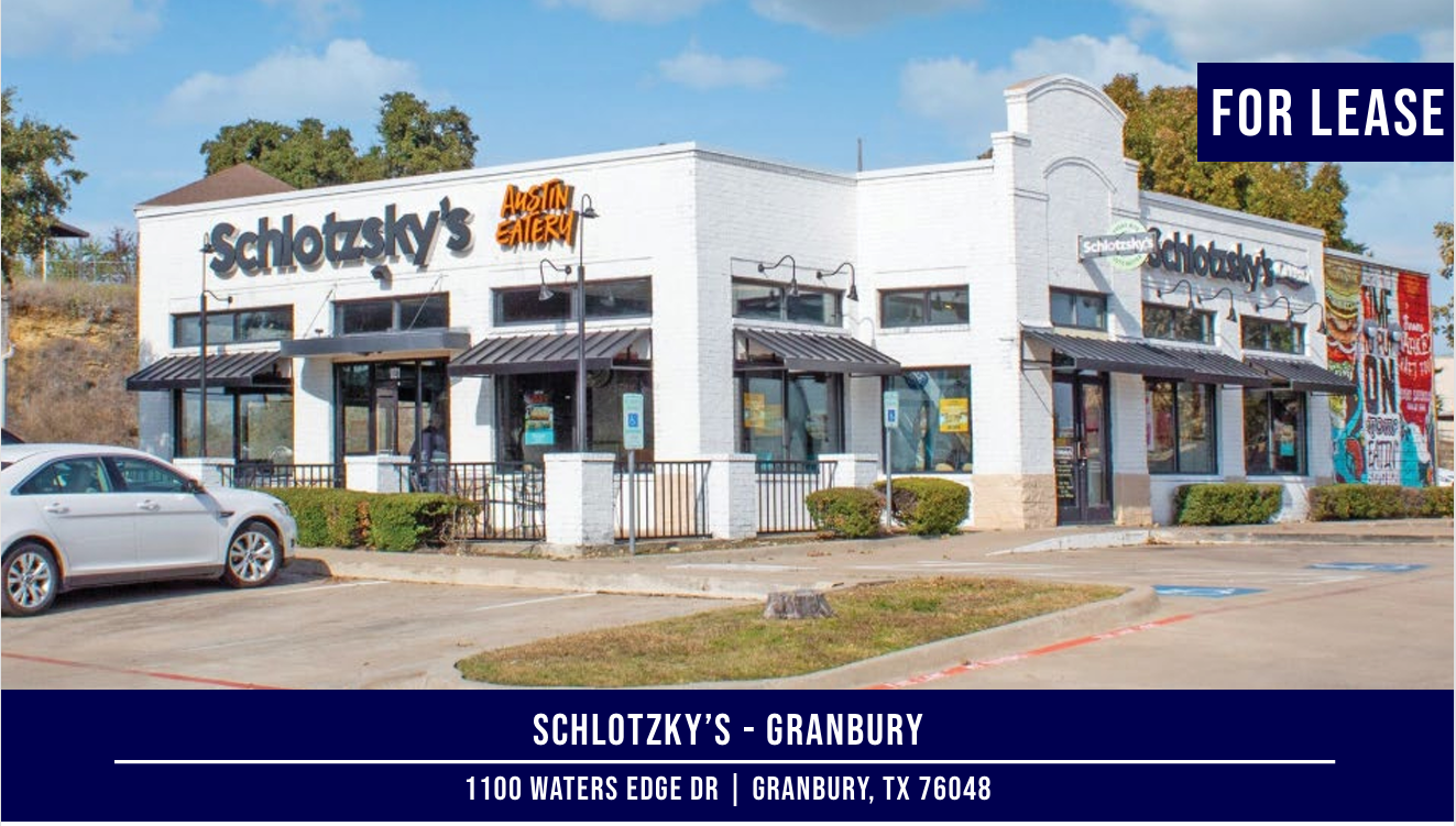 Schlotzsky's building in Granbury, TX, for lease. White exterior, black awnings, and a white car parked outside.