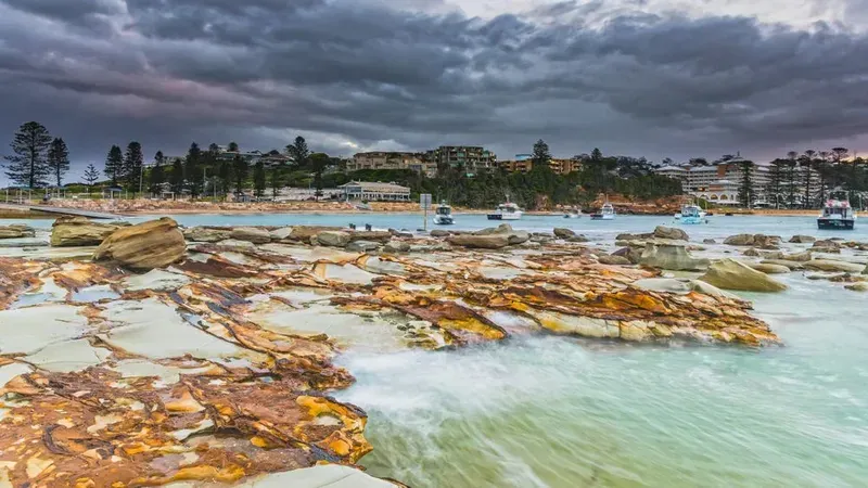 Rocky Shoreline With Orange-toned Stones Meets Turquoise Water — Eurocoast Appliance Service In Gosford, NSW