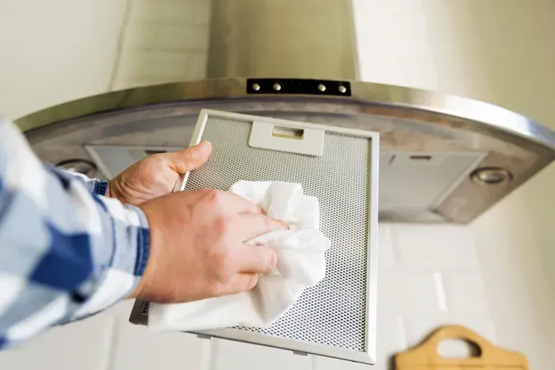 Person in a Plaid Shirt Wipes a Metal Grease Filter — Eurocoast Appliance Service In Tuggerah, NSW