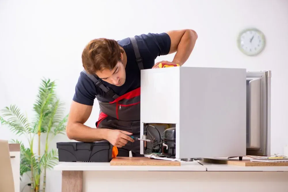 Technician Repairs the Mechanical Components of a Small Refrigerator — Eurocoast Appliance Service In Tuggerah, NSW