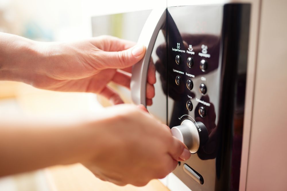 Hands Operating the Controls Microwave in a Kitchen — Eurocoast Appliance Service In Woy Woy, NSW