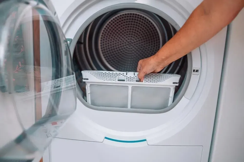 Person Removing the Lint Filter From a White Clothes Dryer — Eurocoast Appliance Service In Gosford, NSW
