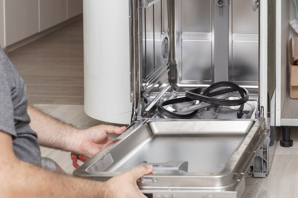 Person Repairs a Dishwasher With the Door Open in a Kitchen — Eurocoast Appliance Service In Woy Woy, NSW