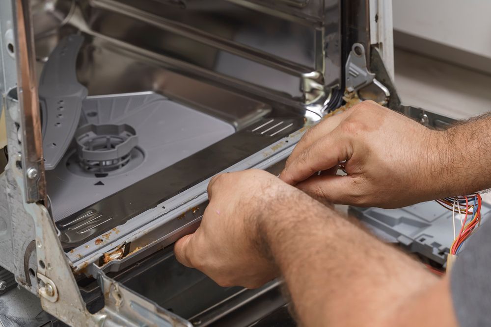 Hands Working to Repair an Open Dishwasher — Eurocoast Appliance Service In Woy Woy, NSW