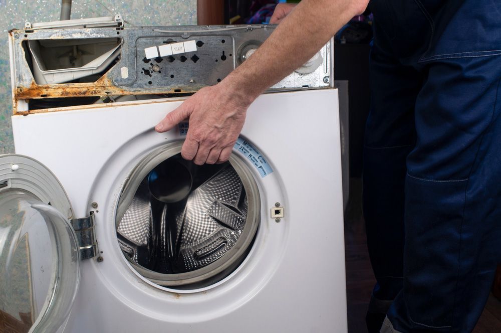 A Person Repairing a White Washing Machine — Eurocoast Appliance Service In Tuggerah, NSW