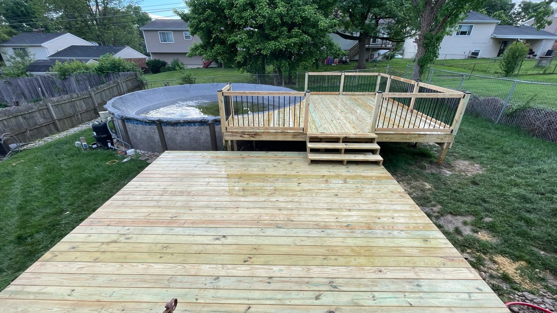A wooden deck next to an above-ground pool. A staircase leads down to the pool deck.