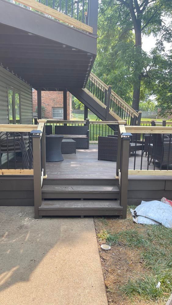 Brown wooden deck with steps leading down to a concrete patio and a second-story deck.