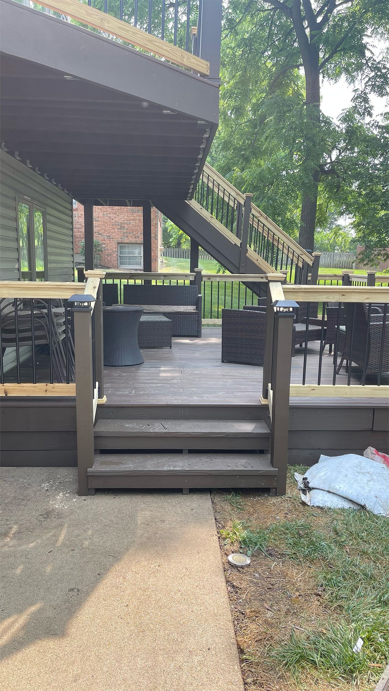 Wooden deck with steps, seating, and railings; brown and tan hues; exterior setting.