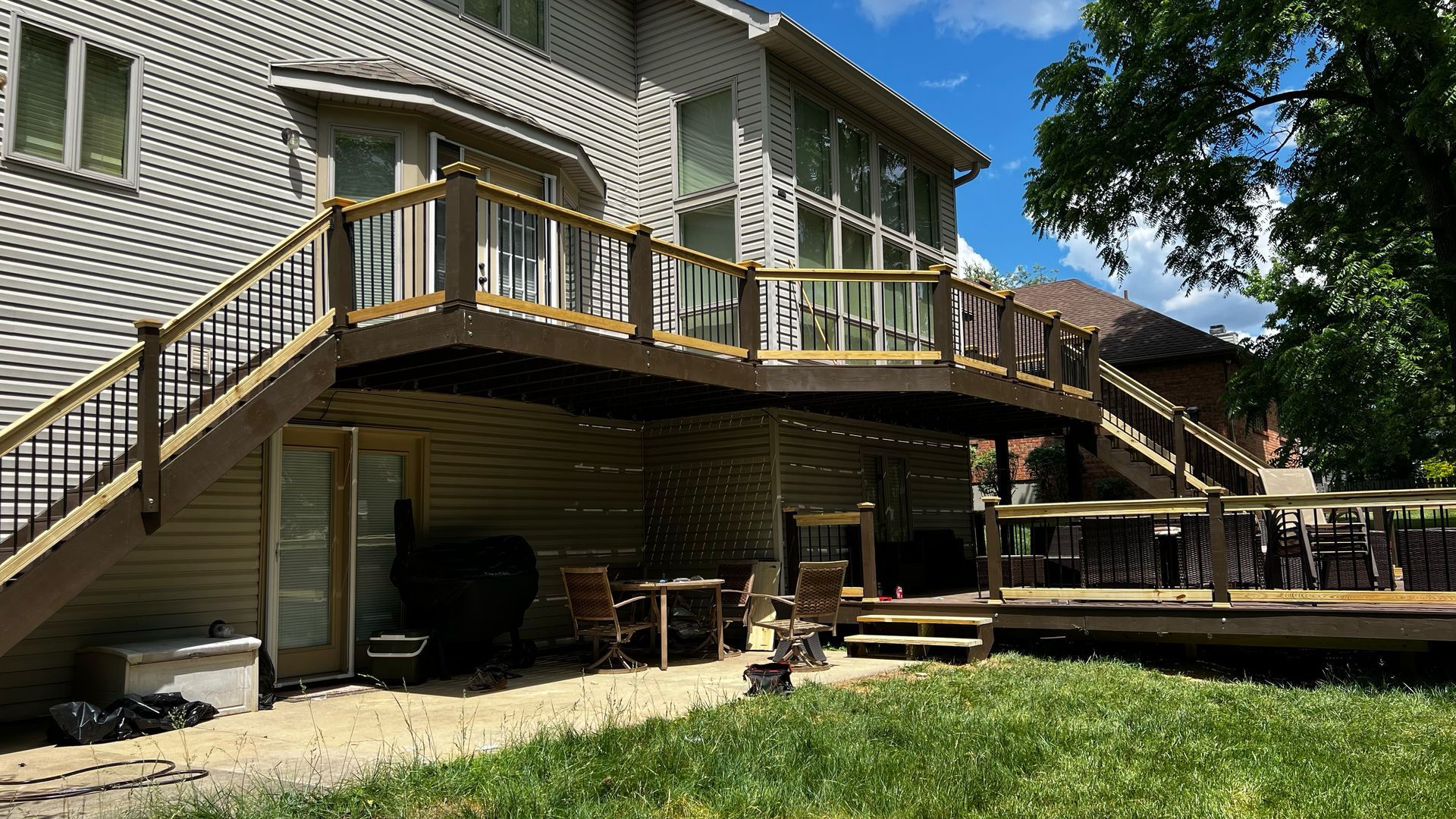 Multi-level wooden deck attached to a house with stairs, railings, and outdoor furniture.