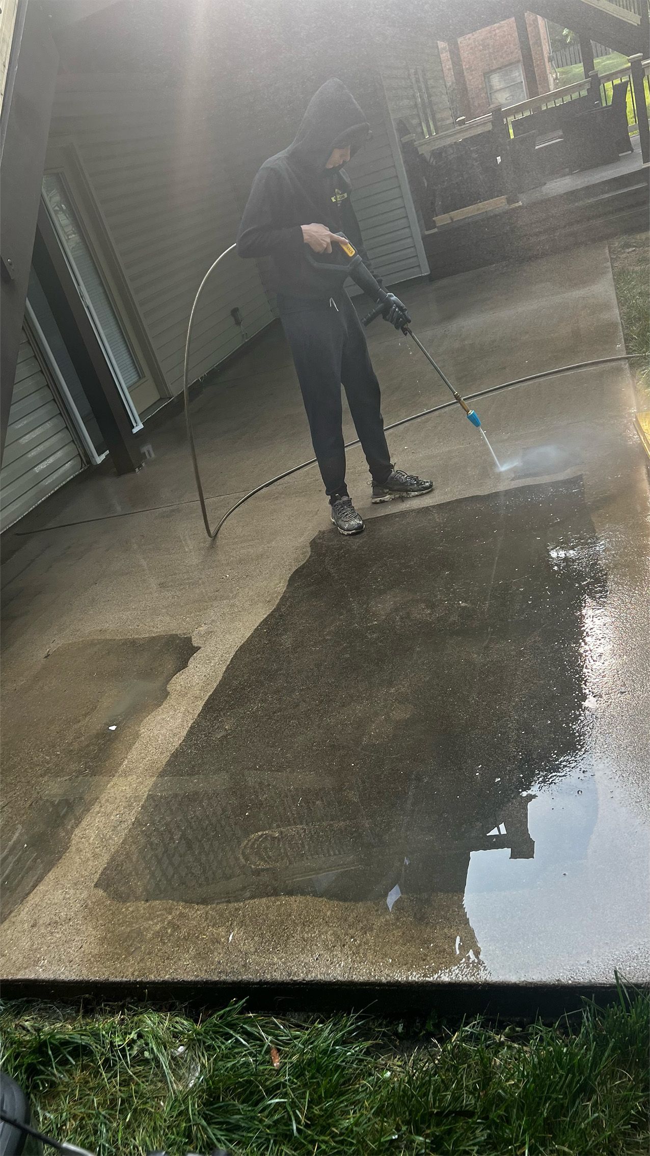 Person using a pressure washer on a concrete patio.