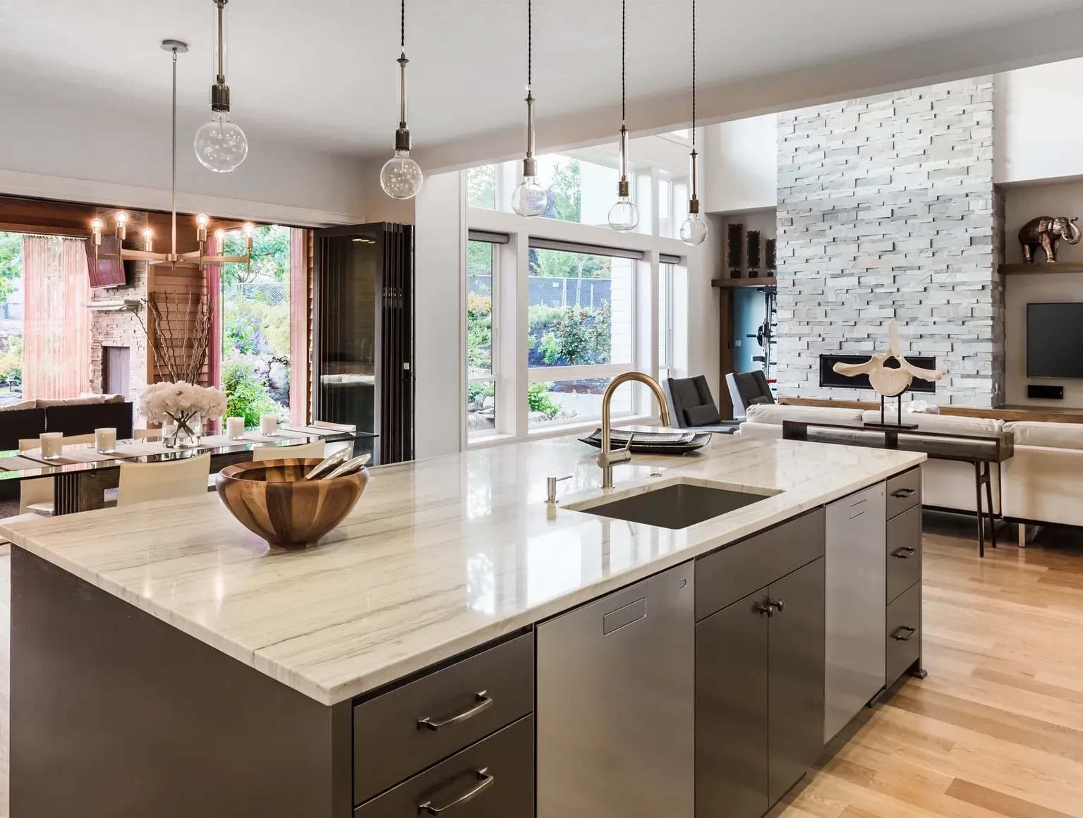 Modern kitchen with large island, marble countertop, and pendant lights.