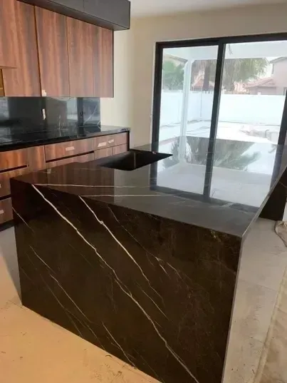 Kitchen with dark granite countertops and cabinets; island with a sink.