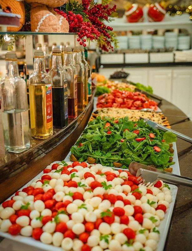 Saladas variadas e molhos engarrafados em um balcão de buffet em um restaurante bem iluminado.