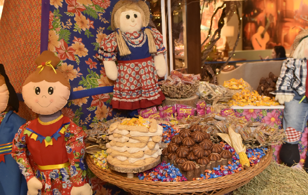 Cestas de vime com doces e guloseimas em uma barraca de mercado festiva, decorada com bonecas coloridas feitas à mão.