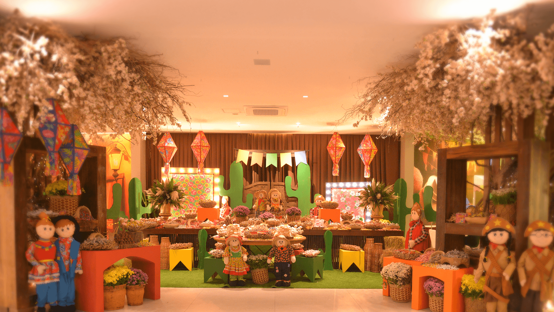 Palco interno decorado com flores, lanternas e bonecas sob luzes aconchegantes.