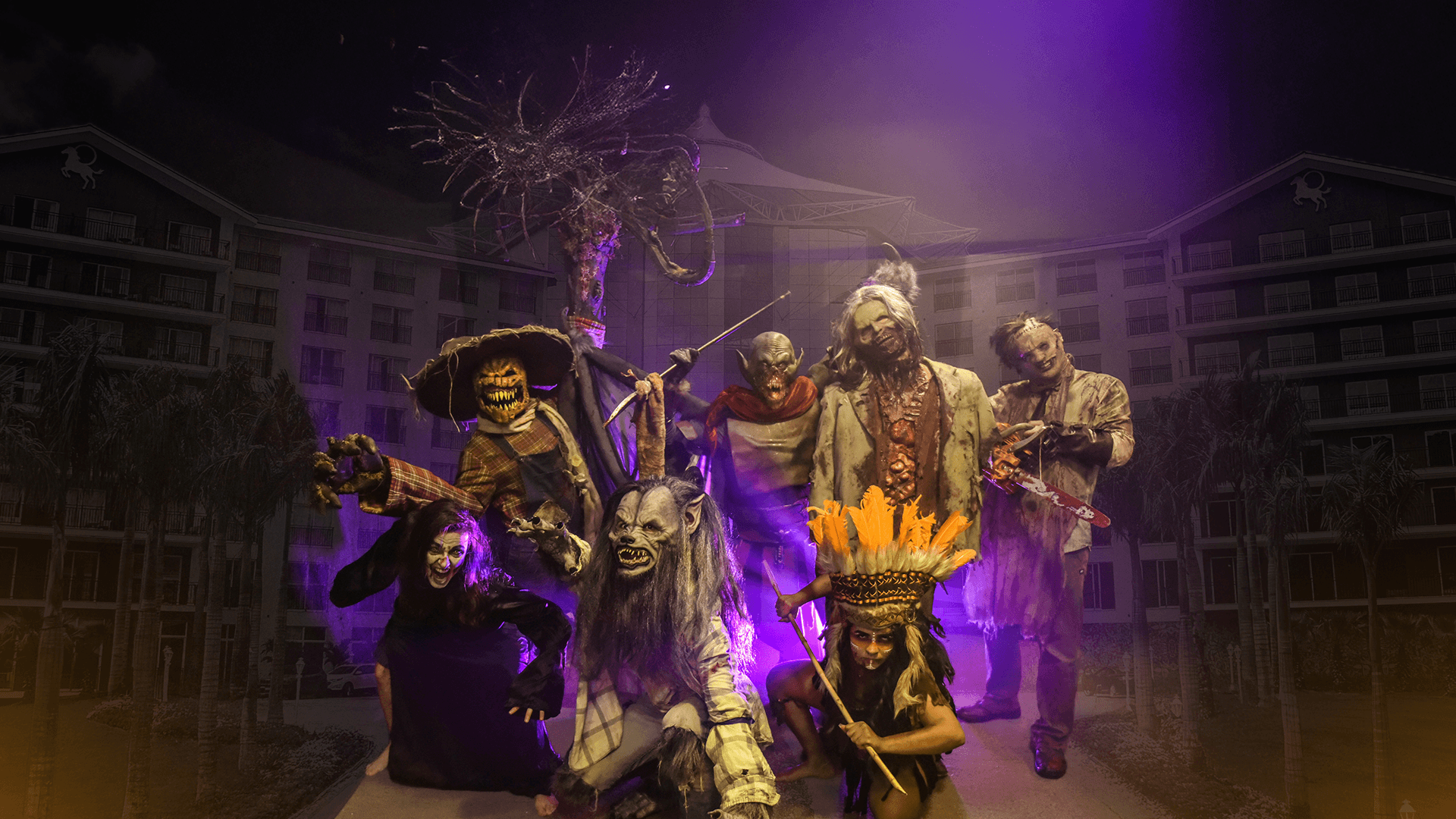 Três artistas fantasiados posam em um cenário gótico iluminado em roxo, cercados por fumaça e adereços misteriosos.
