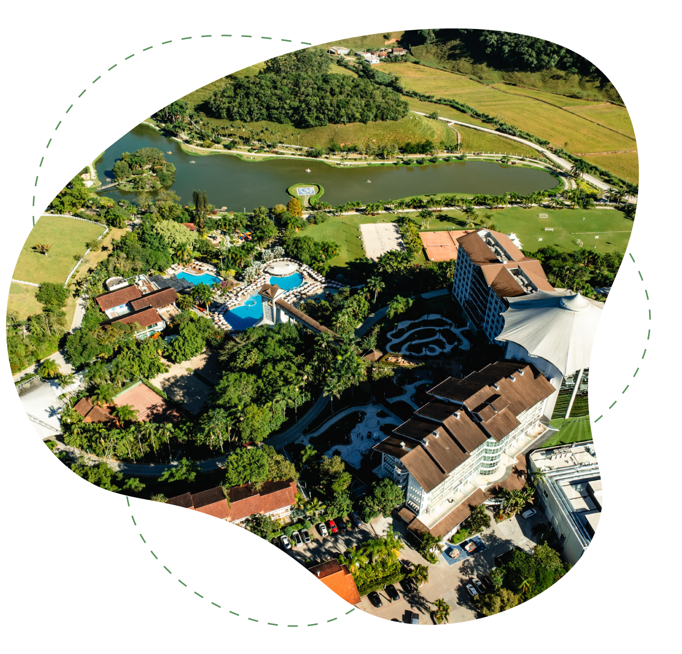 Vale verdejante com edifícios de telhados vermelhos, árvores e colinas sob a luz brilhante do dia.