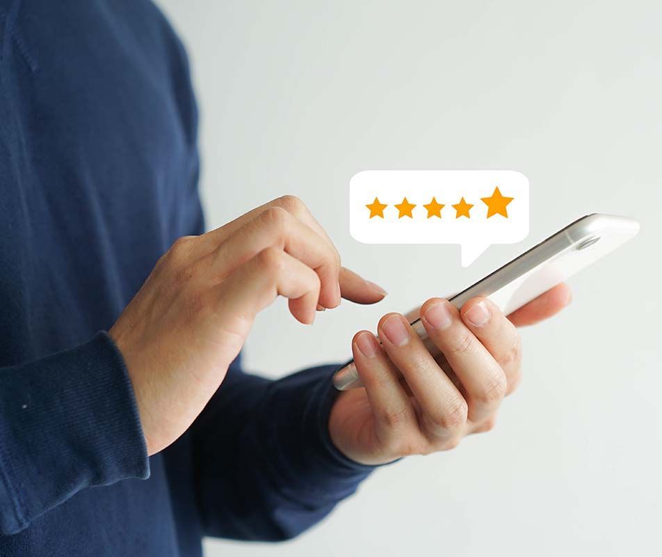 Person using a phone to give a 5-star rating. Orange stars in a speech bubble above the phone.