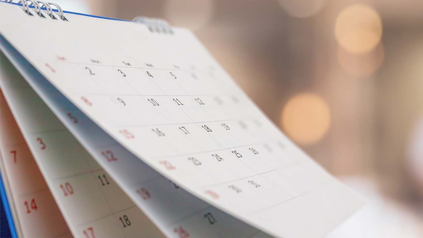 A close-up of a calendar, pages flipped, showing dates.