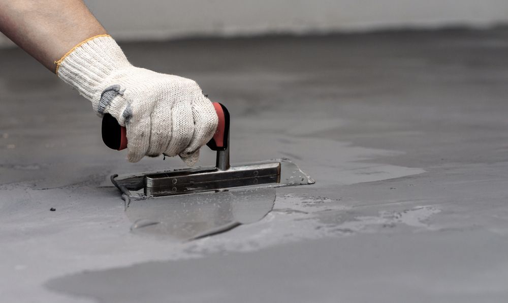 A Person is Using a Trowel to Plaster a Concrete Floor — Tiga's Concreting Services In Branyan, QLD