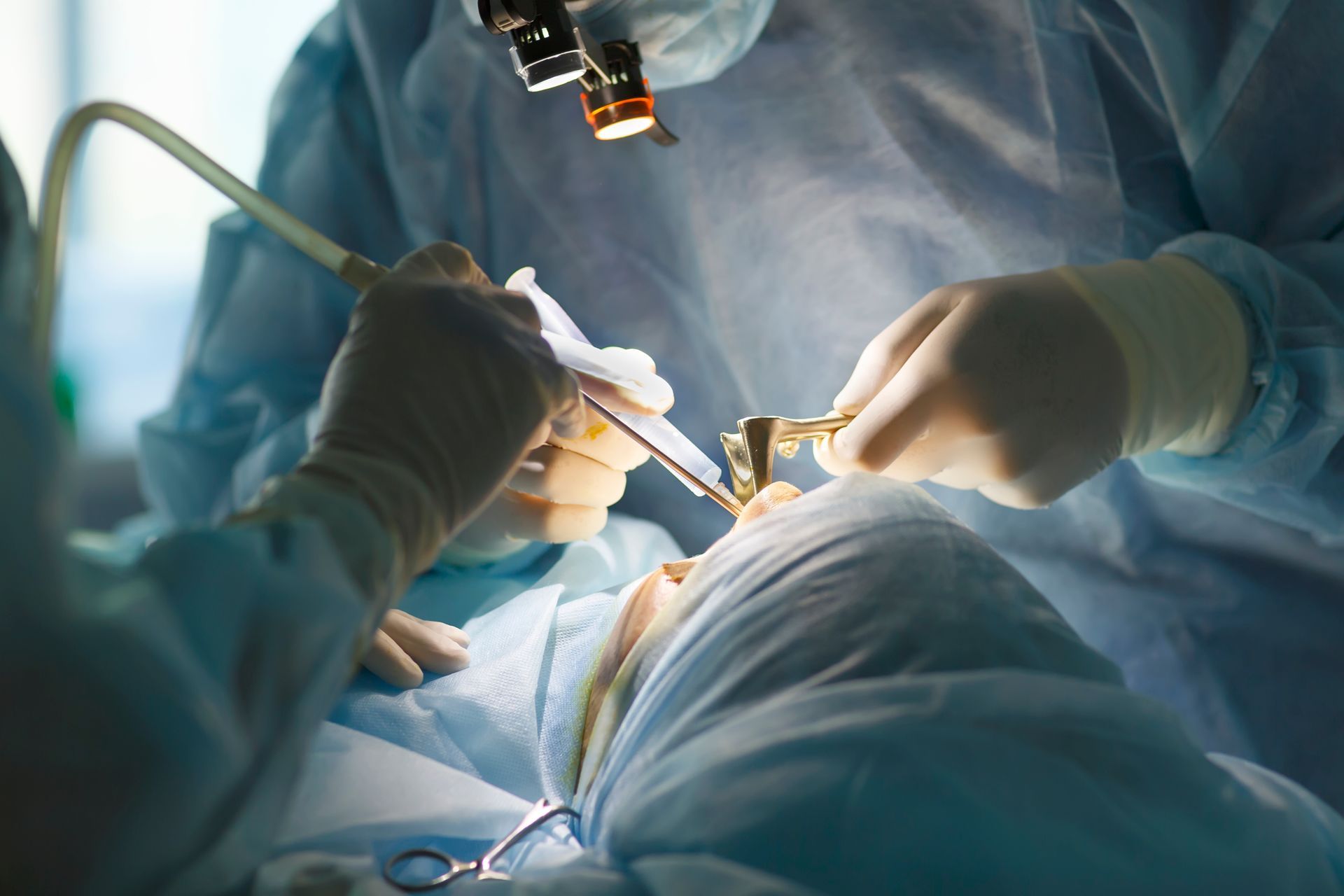 Surgeon and his assistant performing cosmetic surgery on nose in hospital operating room. Surgeon and his assistant performing cosmetic surgery on nose in hospital operating room.