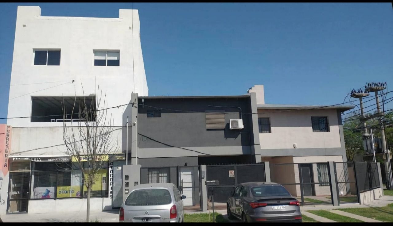 Edificios con diferentes estilos: una torre blanca, un edificio gris y una casa beige bajo un cielo azul.
